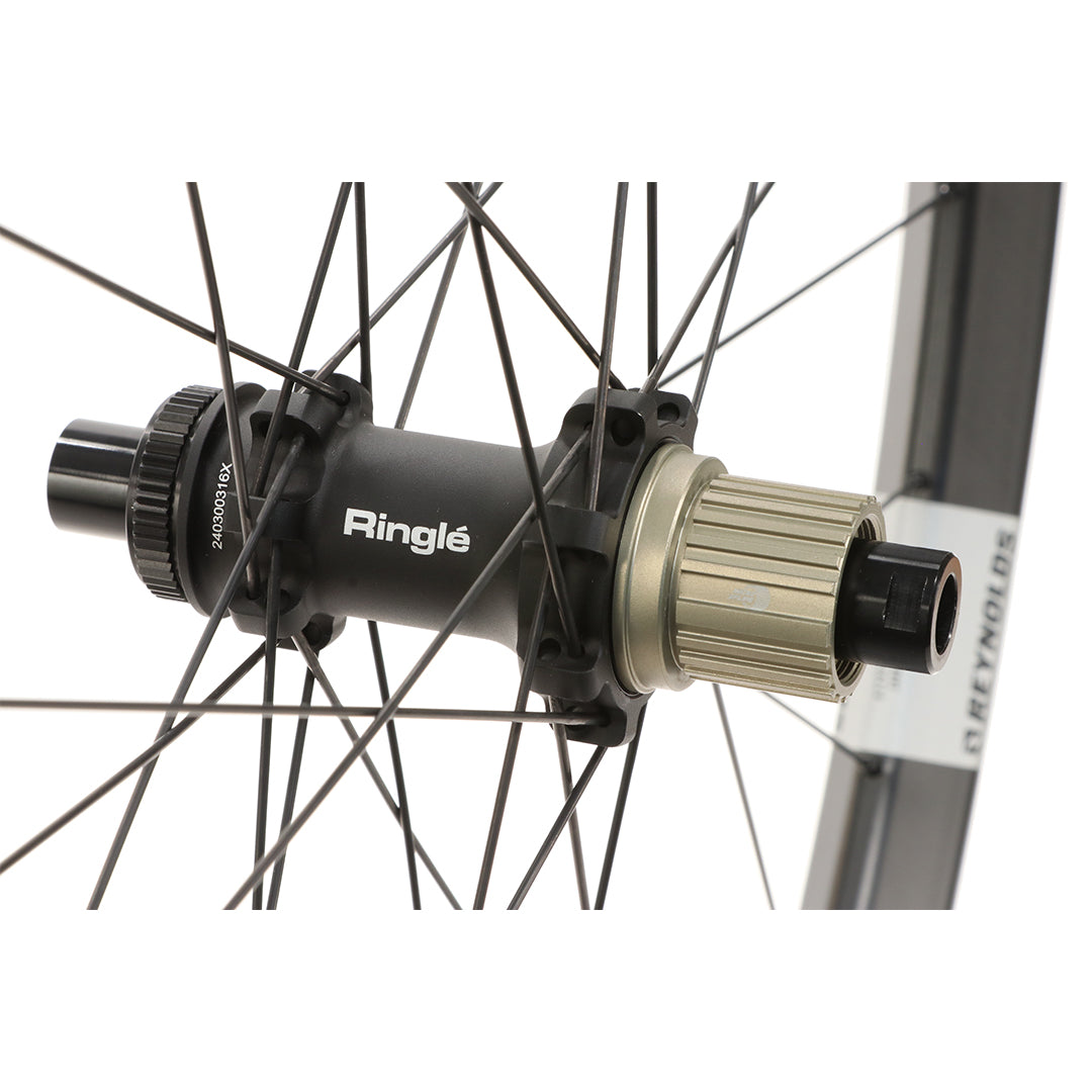 Close-up of a bicycle hub with 'Ringle' branding on Reynolds Trail 309 XC carbon wheel and a white background